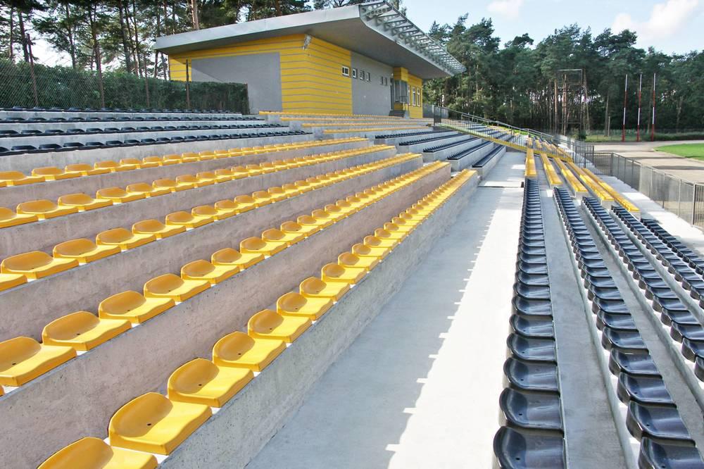 štadiónové sedačky bez operadla - priskrutkované k betónovým schodom na futbalovom ihrisku
