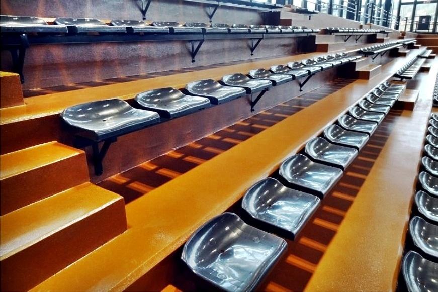 plastové sedačky v športovej hale - bez operadla - kovová konštrukcia pripevnená k stene